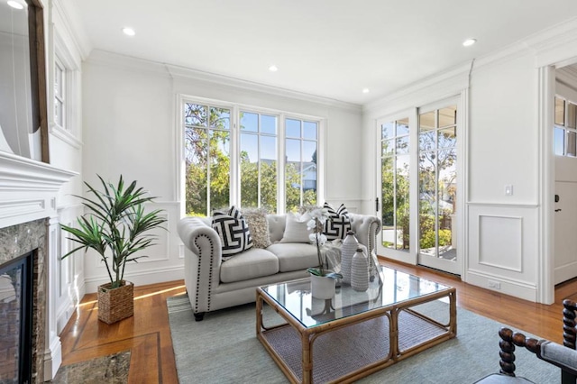 living room featuring a healthy amount of sunlight, wood-type flooring, ornamental molding, and a fireplace