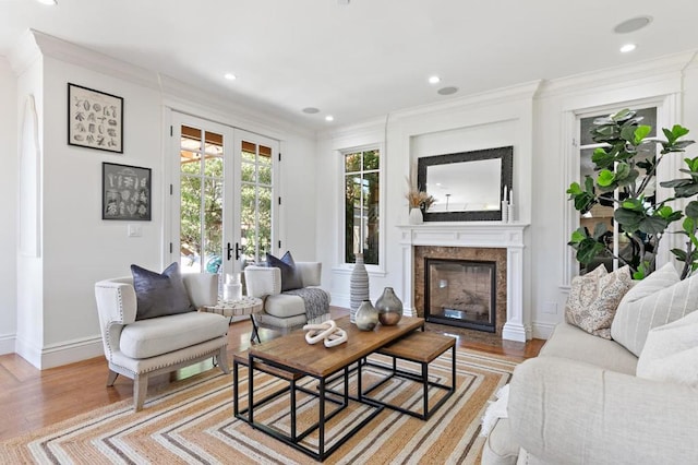 living room featuring crown molding, a high end fireplace, french doors, and light hardwood / wood-style flooring