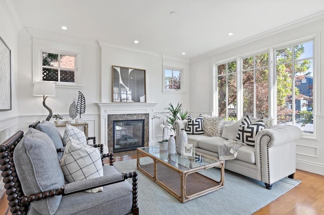 living room featuring a healthy amount of sunlight, light hardwood / wood-style flooring, a fireplace, and crown molding