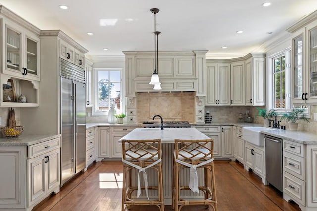 kitchen featuring a breakfast bar, sink, an island with sink, hanging light fixtures, and stainless steel appliances