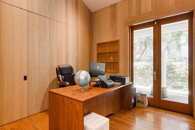 office with light hardwood / wood-style flooring and wood walls