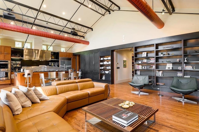 living room with light hardwood / wood-style floors and a towering ceiling