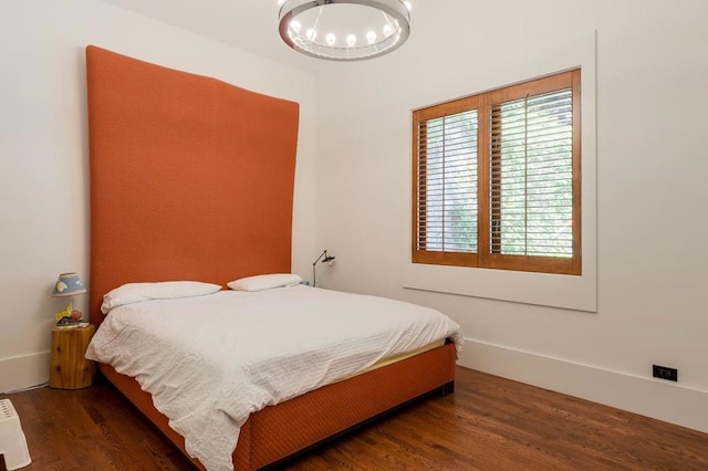 bedroom featuring a notable chandelier and dark wood-type flooring