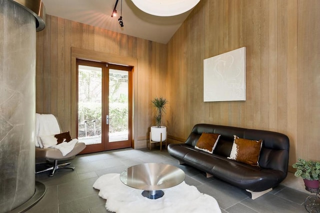 living room with tile patterned flooring, wood walls, and french doors