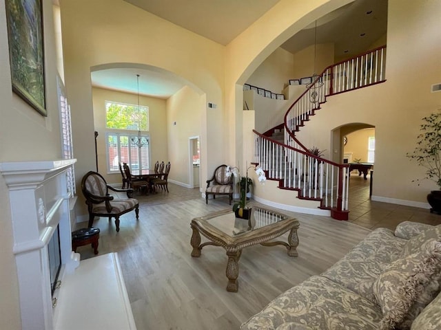 living room featuring light hardwood / wood-style floors, a high ceiling, and an inviting chandelier