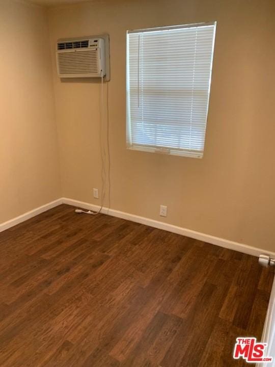 empty room featuring a wall mounted air conditioner and dark wood-type flooring