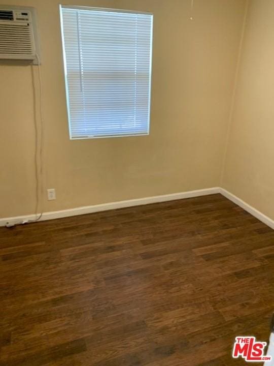 unfurnished room with a wall mounted air conditioner and dark hardwood / wood-style floors