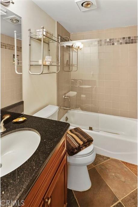 full bathroom with toilet, shower / bath combination with glass door, vanity, and tile flooring