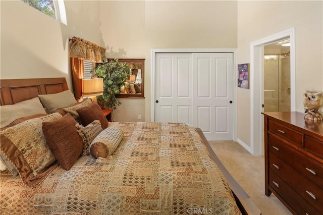 bedroom with a towering ceiling, light carpet, ensuite bathroom, and a closet