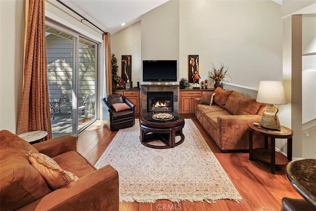 living room with vaulted ceiling, dark hardwood / wood-style floors, and a tiled fireplace