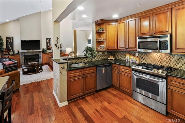 kitchen featuring dark stone counters, hardwood / wood-style floors, stainless steel appliances, sink, and kitchen peninsula