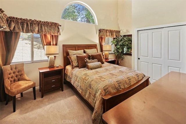 carpeted bedroom featuring a closet and a high ceiling