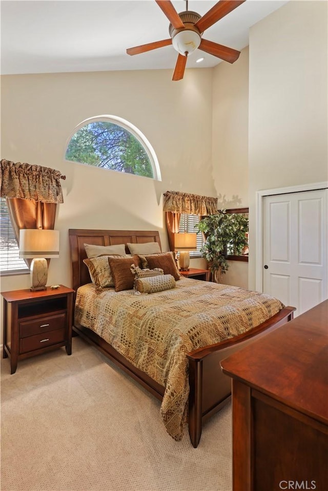 bedroom featuring light colored carpet, ceiling fan, and high vaulted ceiling