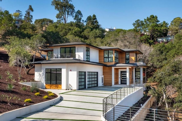 rear view of property featuring a balcony and a garage