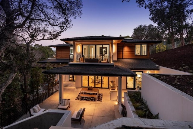 back house at dusk featuring an outdoor hangout area and a patio