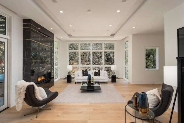 interior space with a tiled fireplace, light hardwood / wood-style floors, and a tray ceiling