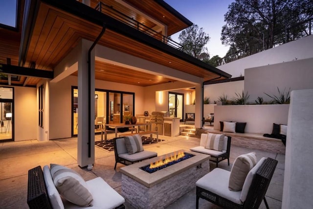 patio terrace at dusk with an outdoor living space with a fire pit