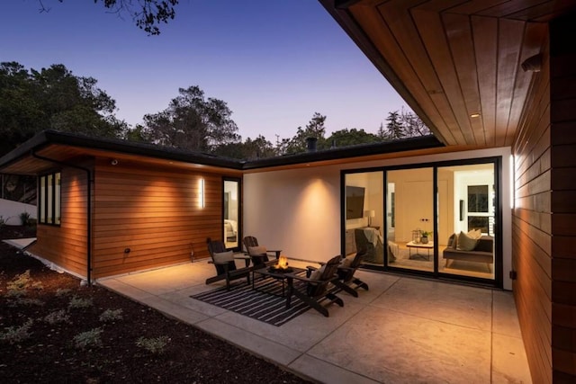 back house at dusk featuring a patio