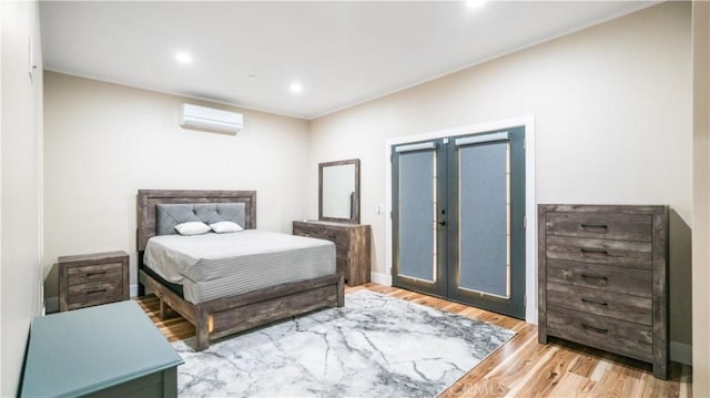 bedroom with a wall mounted air conditioner, access to exterior, and light hardwood / wood-style flooring