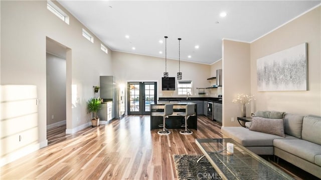 living room featuring ornamental molding, sink, french doors, high vaulted ceiling, and hardwood / wood-style flooring