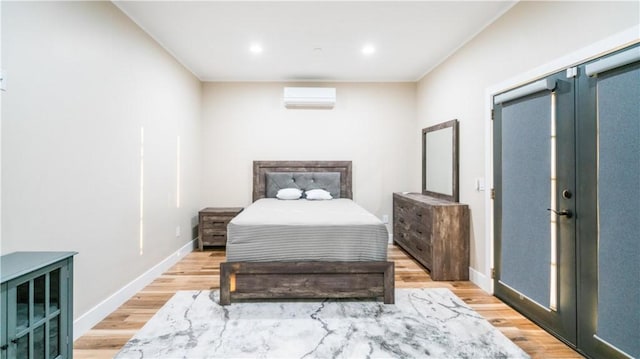 bedroom featuring light hardwood / wood-style floors and a wall mounted AC