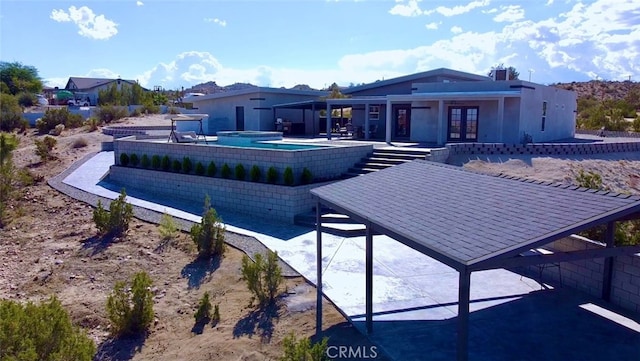 rear view of property with an in ground hot tub and a patio area