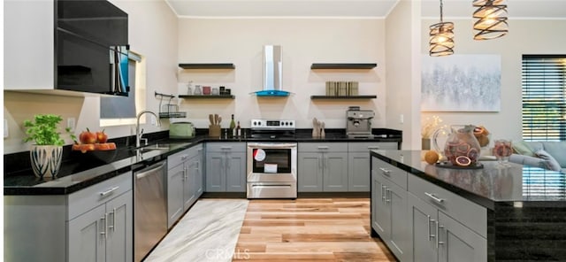 kitchen featuring gray cabinetry, wall chimney exhaust hood, sink, light hardwood / wood-style floors, and appliances with stainless steel finishes