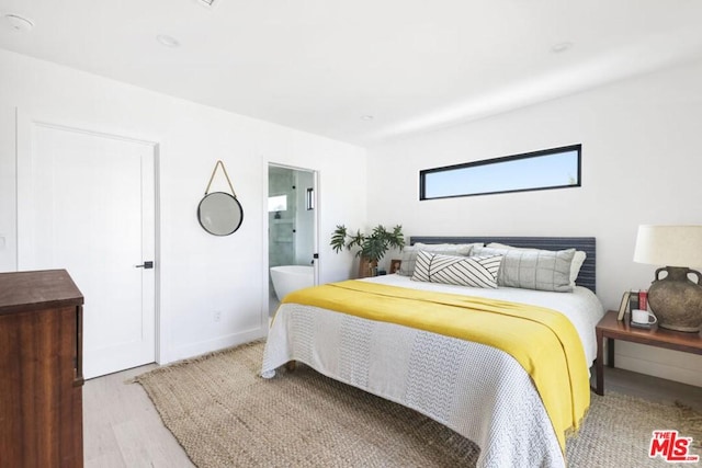 bedroom featuring light wood-type flooring and ensuite bath