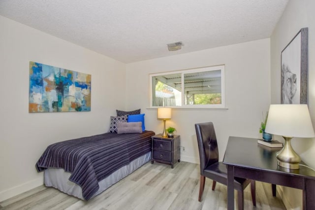 bedroom with a textured ceiling and light wood-type flooring