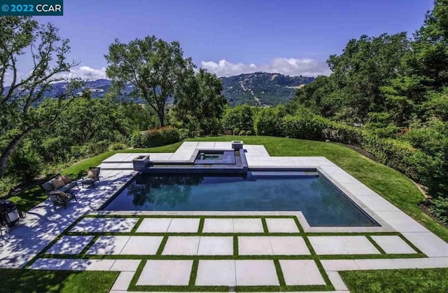 view of swimming pool featuring a mountain view, a patio area, and a yard