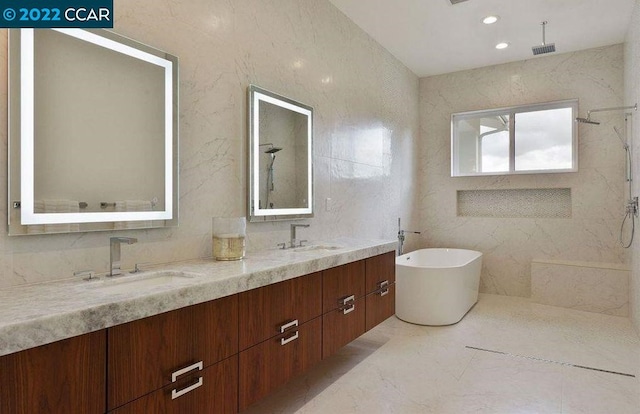 bathroom featuring dual bowl vanity, tile walls, and a bathing tub