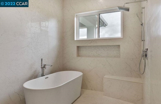 bathroom with a tub and tile walls