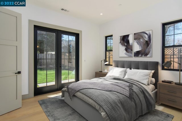 bedroom with french doors, light hardwood / wood-style floors, access to outside, and multiple windows