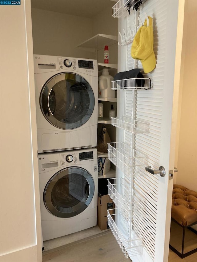 washroom featuring stacked washing maching and dryer and light hardwood / wood-style flooring