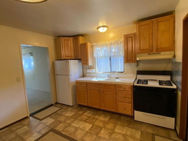 kitchen featuring white appliances, tile countertops, sink, and light tile floors