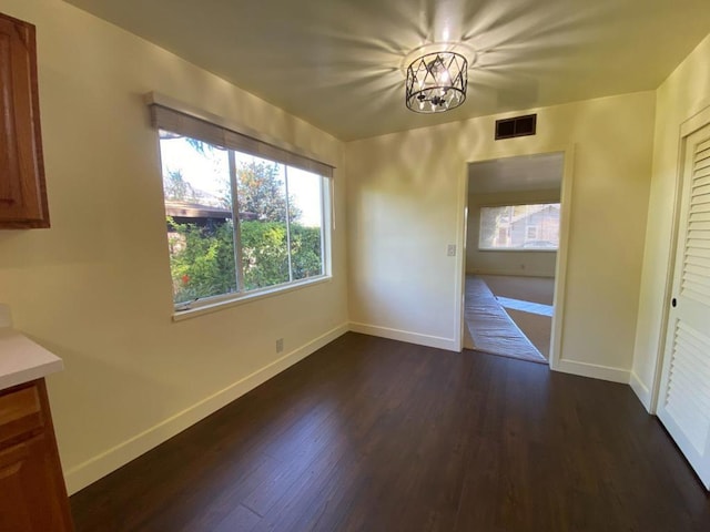 unfurnished room featuring dark hardwood / wood-style flooring and an inviting chandelier