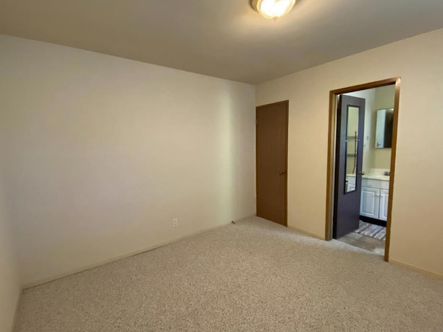 unfurnished bedroom featuring light carpet and connected bathroom