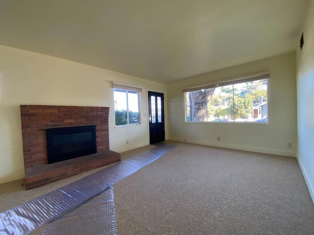 unfurnished living room with a brick fireplace and light carpet