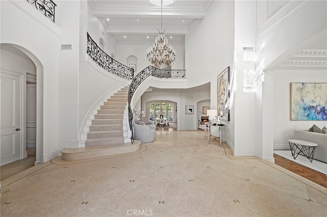 foyer entrance with ornamental molding, coffered ceiling, a high ceiling, beam ceiling, and a notable chandelier