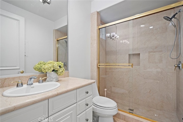 bathroom featuring toilet, vanity, and a shower with door