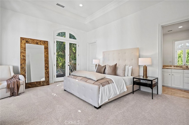 bedroom featuring connected bathroom, a tray ceiling, access to exterior, and light colored carpet