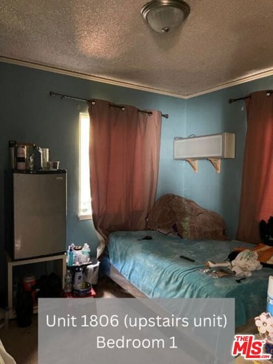 bedroom with a textured ceiling and ornamental molding