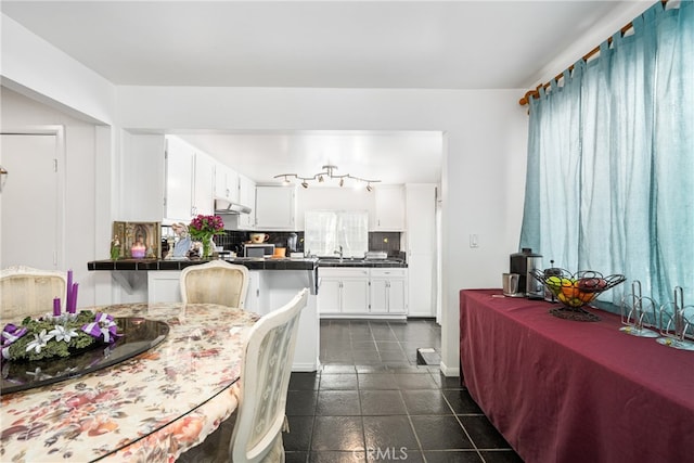 kitchen with backsplash, tile countertops, sink, white cabinetry, and dark tile floors