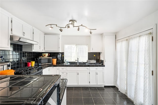 kitchen featuring tasteful backsplash, stainless steel appliances, dark tile flooring, tile counters, and white cabinetry