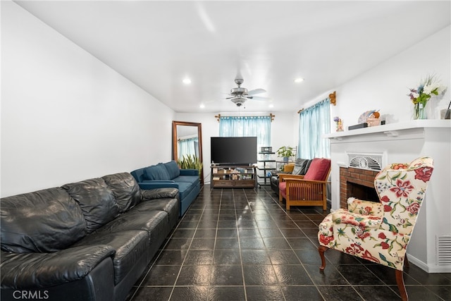 living room featuring a brick fireplace, dark tile floors, and ceiling fan