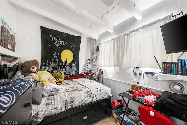 bedroom with light tile floors and beamed ceiling