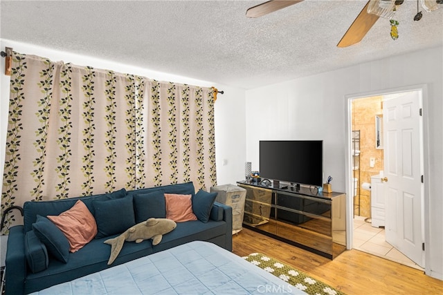 tiled bedroom featuring ceiling fan, a textured ceiling, and ensuite bath