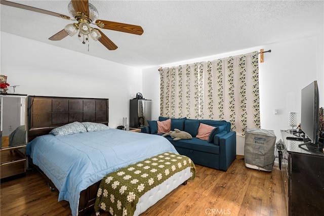 bedroom featuring ceiling fan, hardwood / wood-style floors, and a textured ceiling