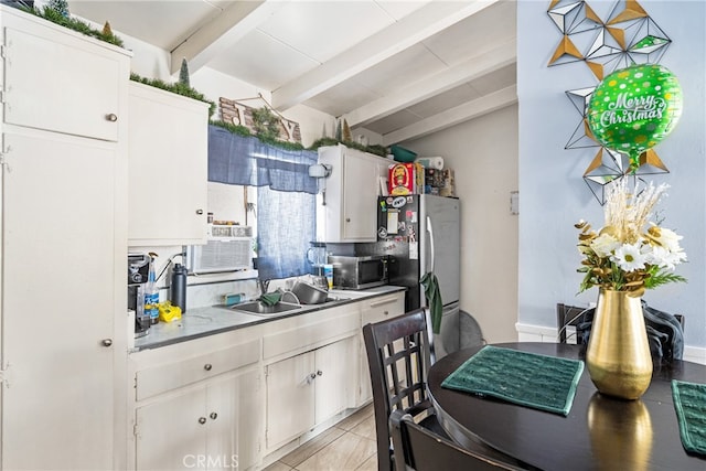 kitchen featuring white cabinetry, sink, stainless steel appliances, light tile floors, and lofted ceiling with beams