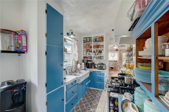 kitchen featuring sink, plenty of natural light, light tile patterned flooring, and blue cabinets